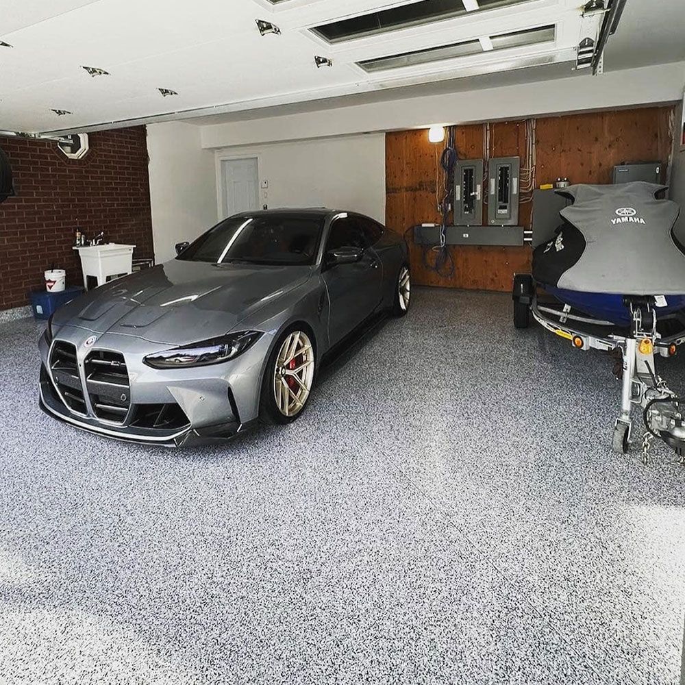 Garage double avec plancher d'époxy à flocons gris et voiture stationnée