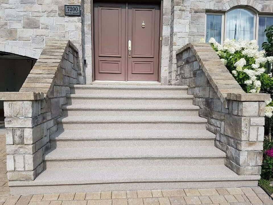 Grand escalier d'entrée entre deux murets de pierre, refait au revêtement acrylique